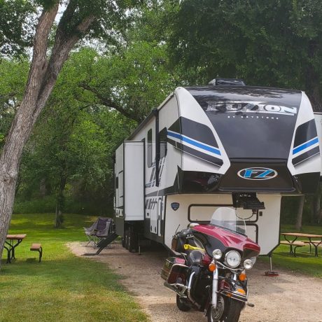 Large fifth wheel backed into a shady RV site.