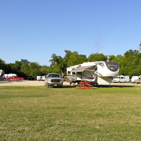 5th wheel pulled into a large pull thru rv site with a huge grassy field around it